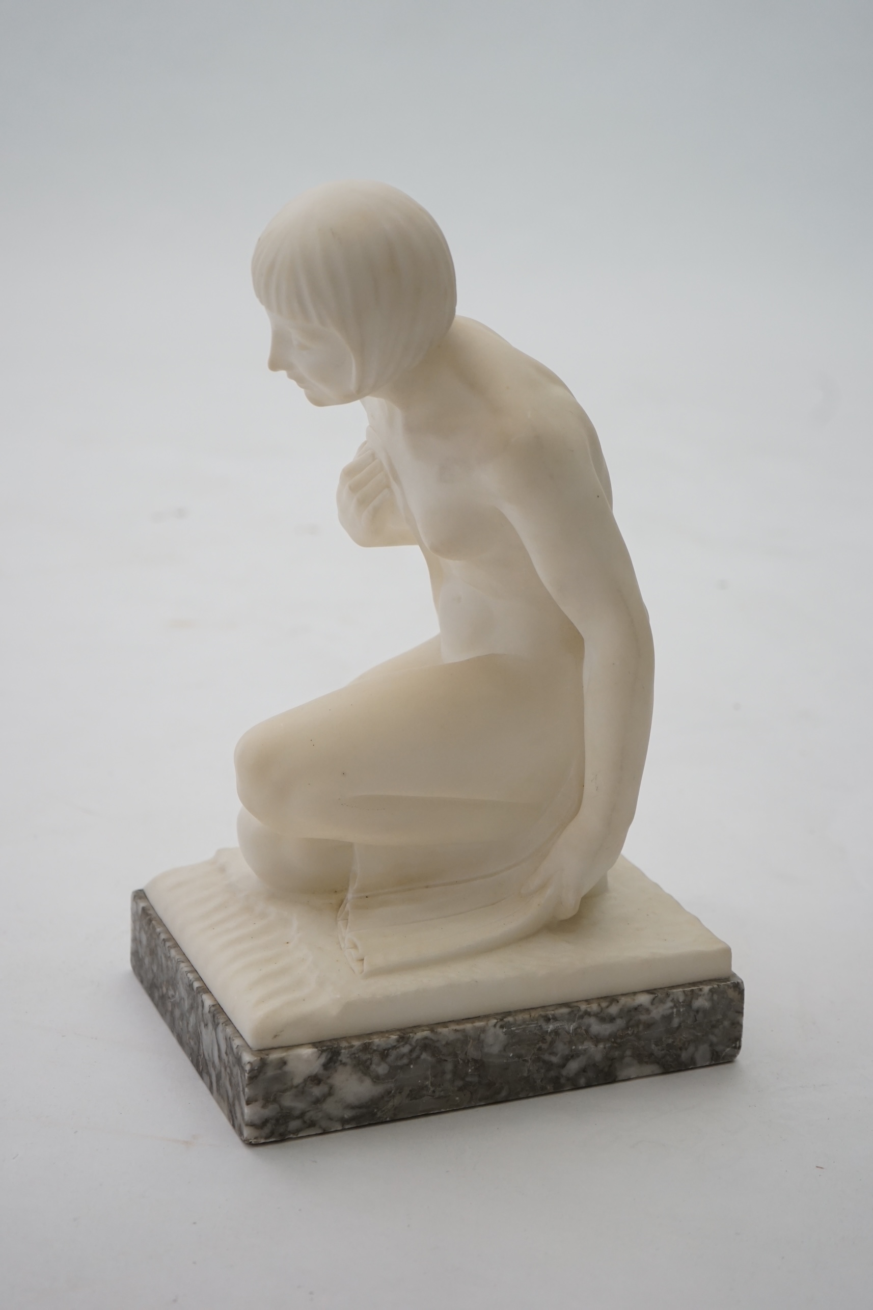 Manner of Gugliemo Pugi (1850-1915). An Italian Art Deco carved marble figure of a crouching bather kneeling and semi-draped